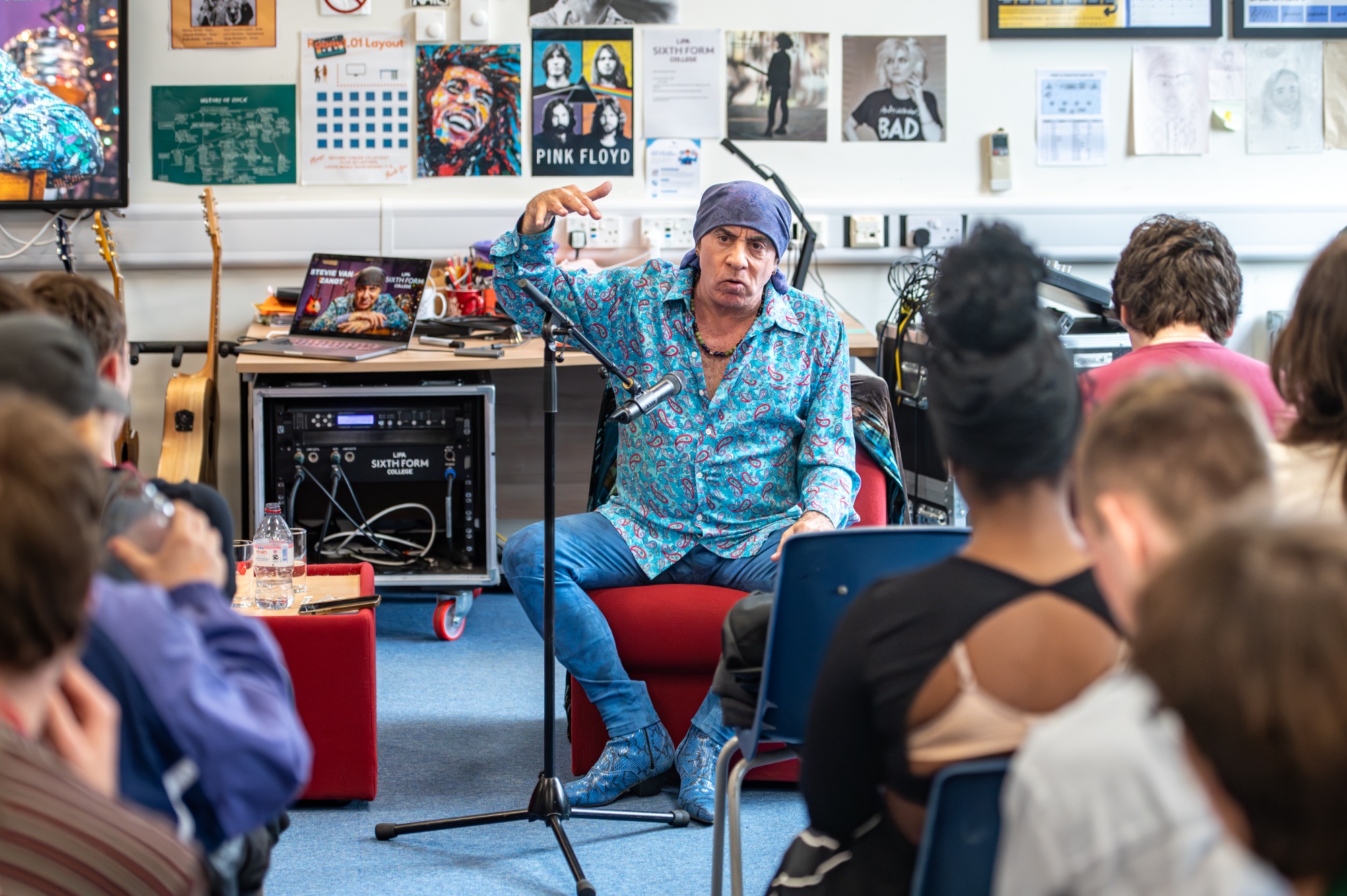 Steve sits on a seat at the front of the classroom in front of the students during his Q&A. 