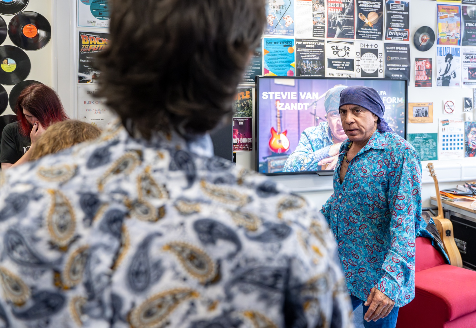 Stevie chats with a student in the classroom while they prepare their performance. 