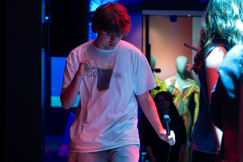 Singer dances on stand with a mic in his hand.;