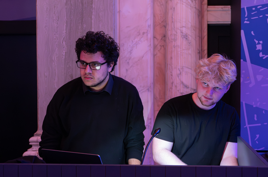 Two sound technicians working at the back of the performance.