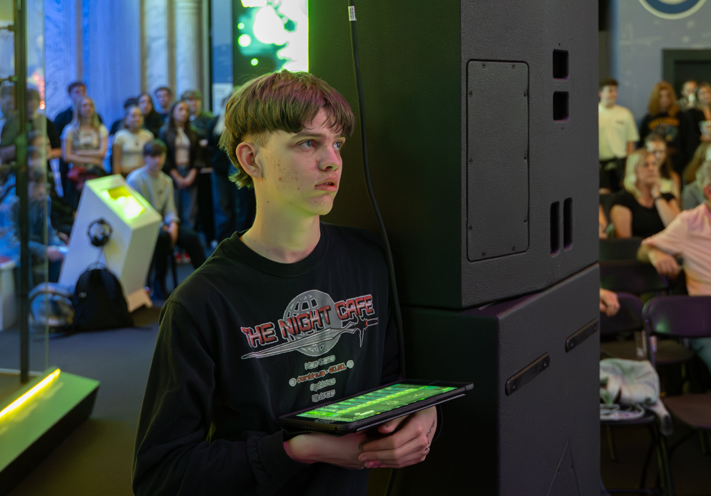 Sound technician stands with a tablet, monitoring the performance.