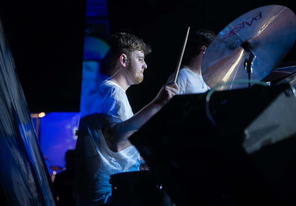 Drummer plays as part of the 8-piece band.