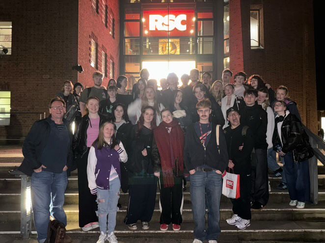 Students stand outside theatre on a trip.