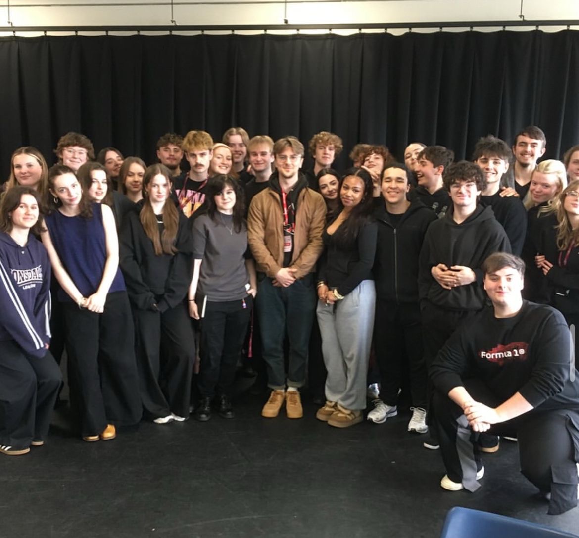 Students stand with professional at the end of a masterclass.