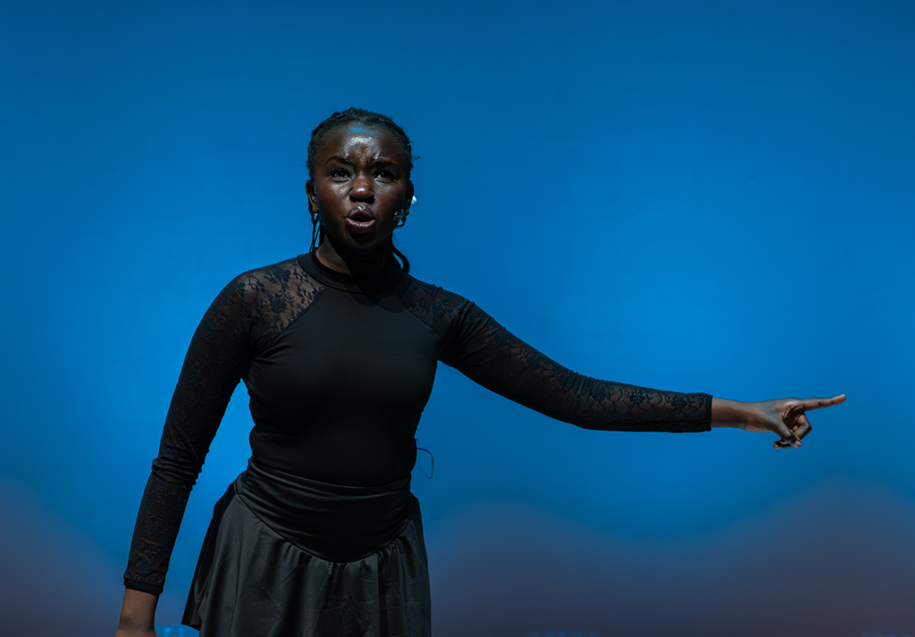 A student looks to the audience whilst pointing to their left. 