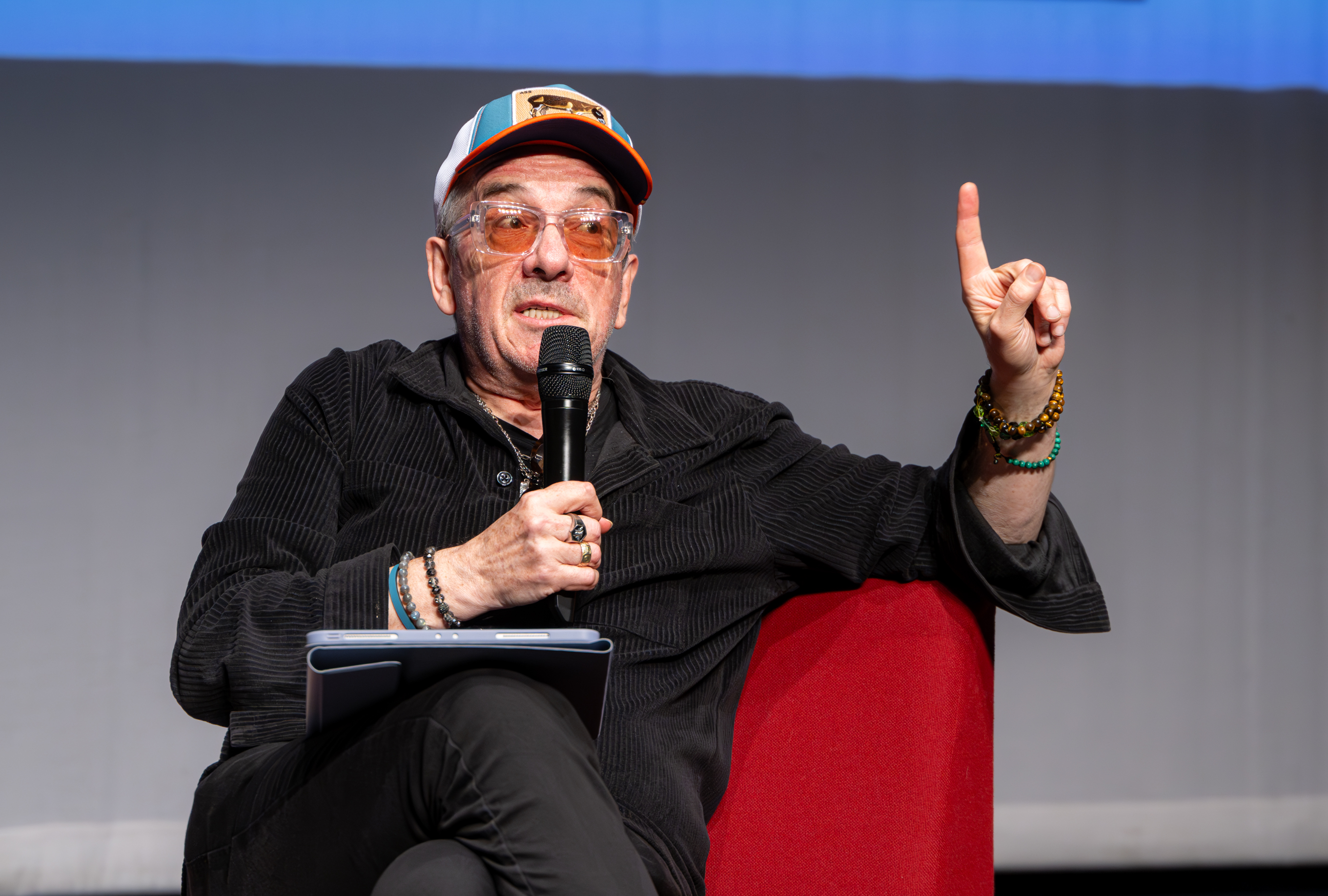 Elvis Costello sat speaking into a microphone during a live Q&A.