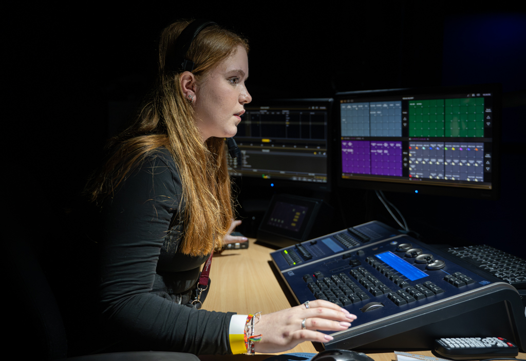Sound tech student at her desk working during a rehersal. 