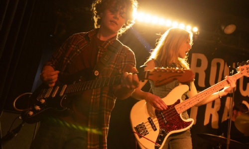 Two students playing electric guitars on stage